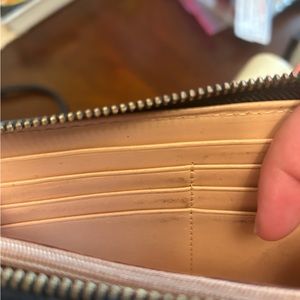 Black leather Kate spade zipper wallet. White stitching detail along edges.